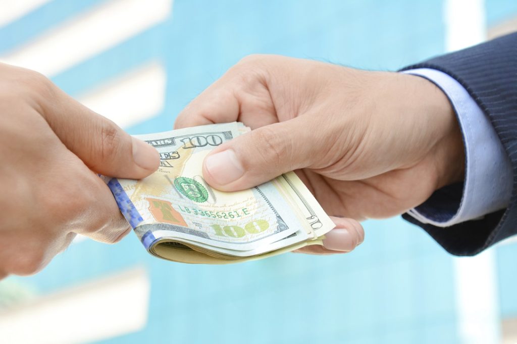 Hand receiving money, US dollars, from businessman - bribery concept